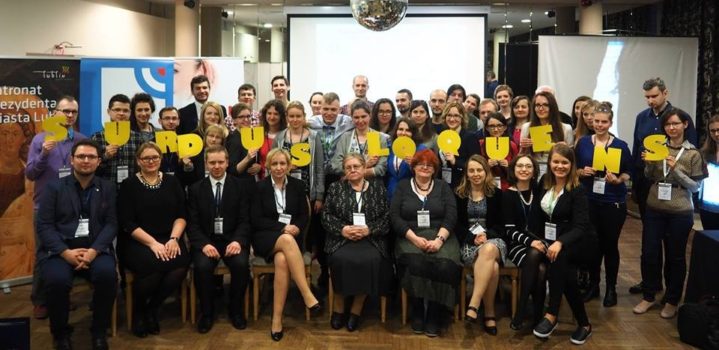 Zdjęcie przedstawiające grupę ludzi, gości konferencji. Część osób trzymając w rękach żółte litery tworzy napis: SURDUS LOQUENS