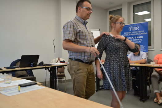trenerzy katarzyna Balwierz oraz artur then pokazują uczestnikom szkolenia bliżej dostępności jak wspierać osobę niewidomą poruszającą się z laską