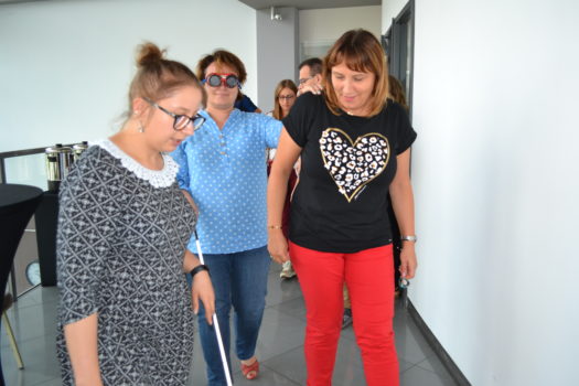 trenerka katarzyna baliwerz tłumaczy dwóm kobietom, jedna z laską - jak spierać osobę niewidomą podczas poruszania się