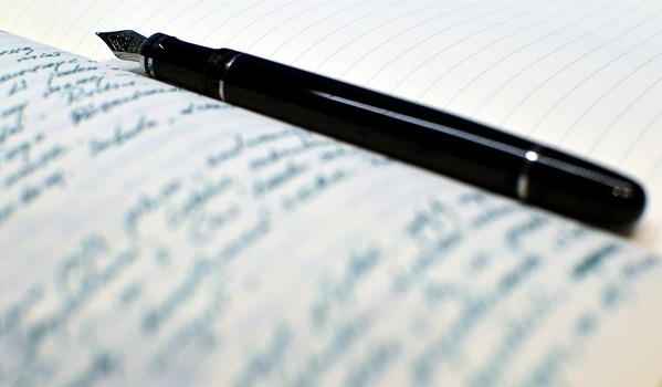 czarne pióro do pisania leżące na zapisanej stronie notatnika