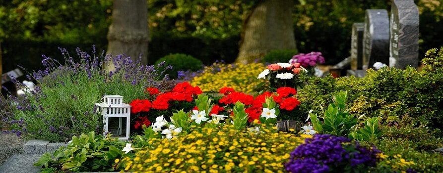 grób z kolorowymi kwiatami i białym lampionem