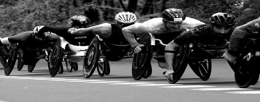 Czarno-białe zdjęcie z wyścigów kolarskich zawodników na sportowych wózkach inwalidzkich