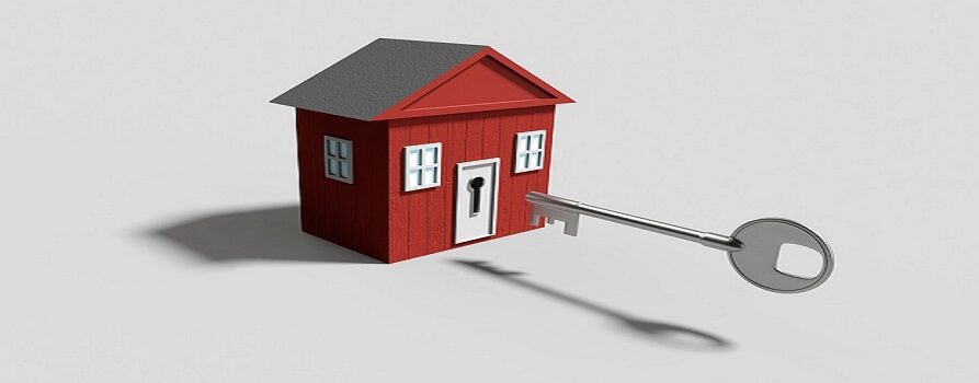Grafika: czerwony, drewniany domek, naprzeciwko niego duży klucz