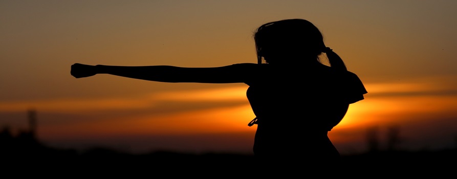 kobieta, ćwicząca sztuki walki przy zachodzie słońca
